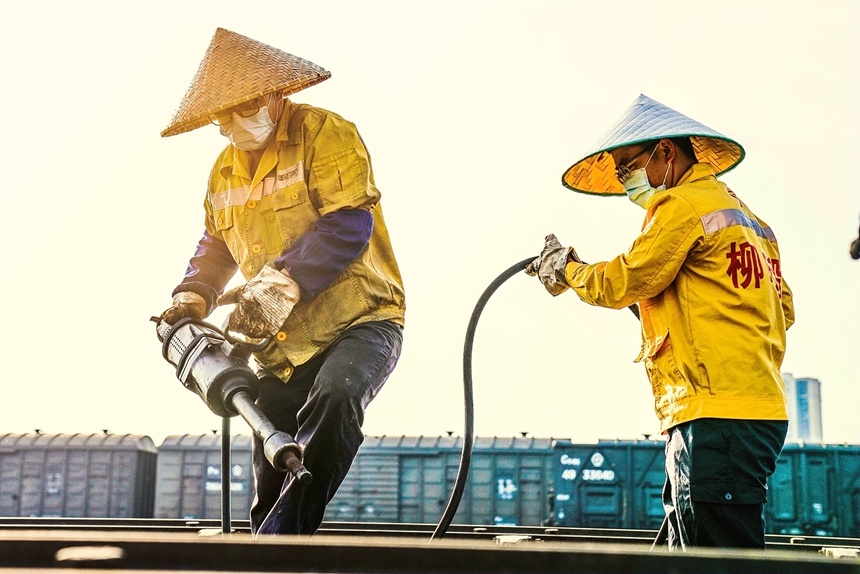 職工在烈日下用風(fēng)動扳手拆卸制動鉗螺絲。