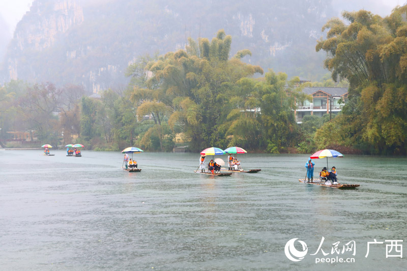 人們雨中乘坐竹筏欣賞遇龍河美景。人民網(wǎng) 付華周攝