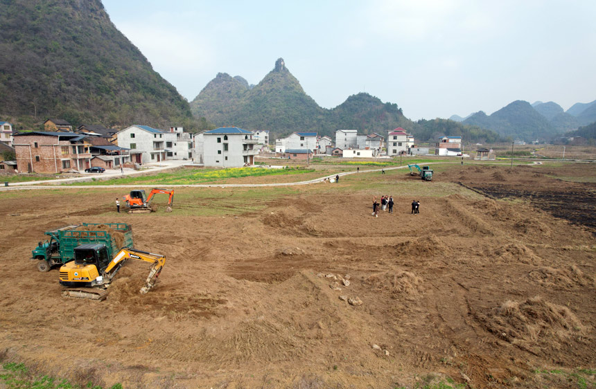 在融安縣橋板鄉(xiāng)古丹村田地里，幾臺(tái)挖掘機(jī)正在進(jìn)行土地平整。