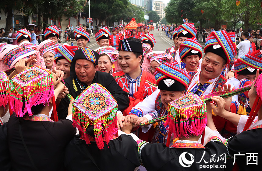 “差人”給圍觀群眾發(fā)喜糖，給新郎擋“羞”繡巾，給攔路人發(fā)“檳榔”，迎親隊伍才成功“沖關(guān)”。人民網(wǎng)記者 彭遠賀攝