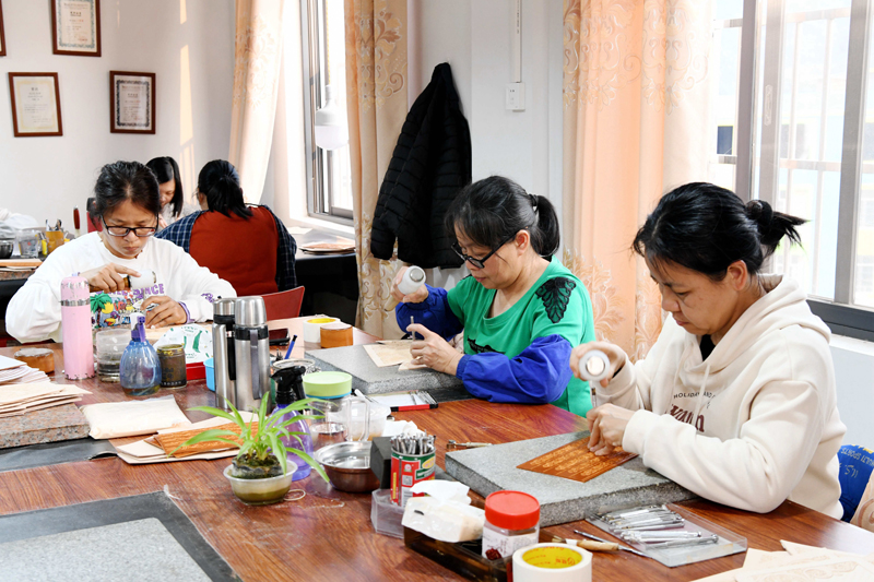 松山村的村民在皮具公司給皮料雕花