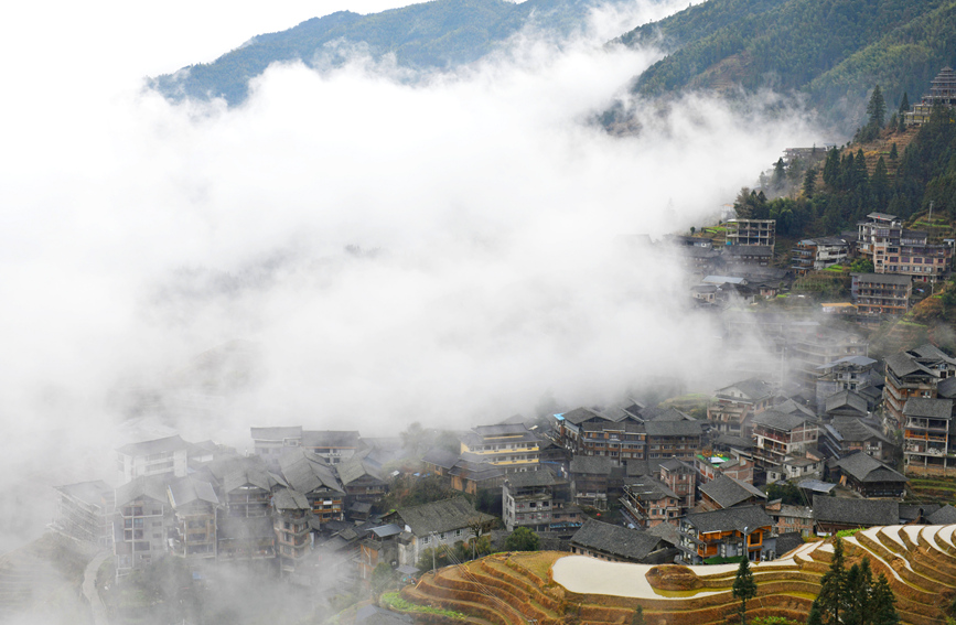 層層疊疊的梯田和錯落有致的吊腳樓在云海間若隱若現(xiàn)