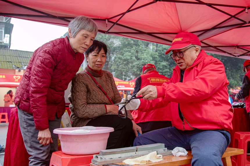 圖為志愿者為市民磨剪刀。蔣少闐攝