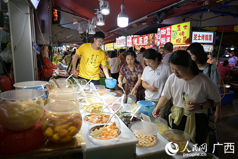 南寧埌西夜市一家酸嘢攤前，顧客在選購酸嘢。人民網(wǎng) 雷琦竣攝